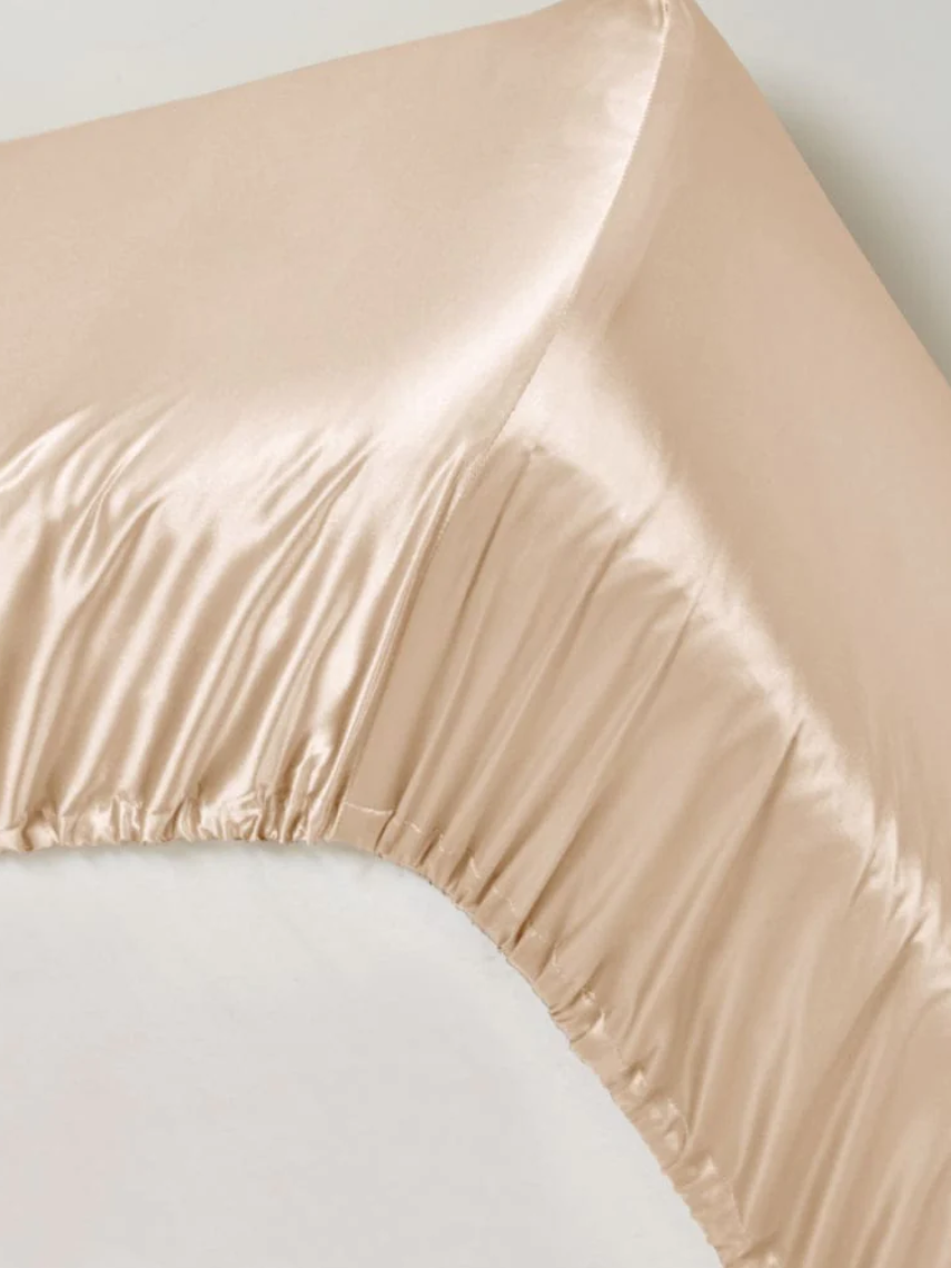Champagnefarvet satin-lagen med elastisk kant og glansfuld, glat overflade